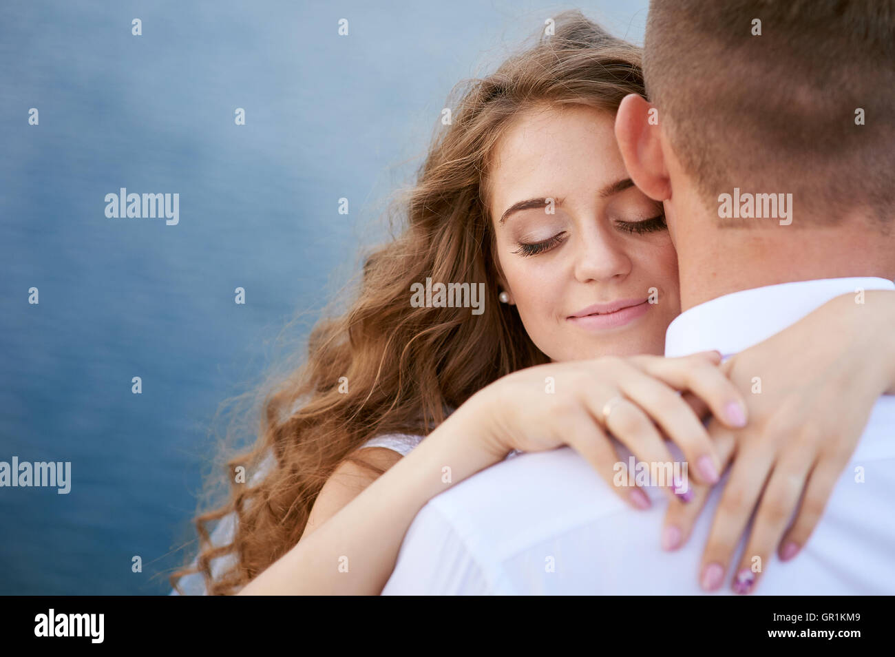 Les jeunes mariés et bride hugging sur le fond du lac Banque D'Images