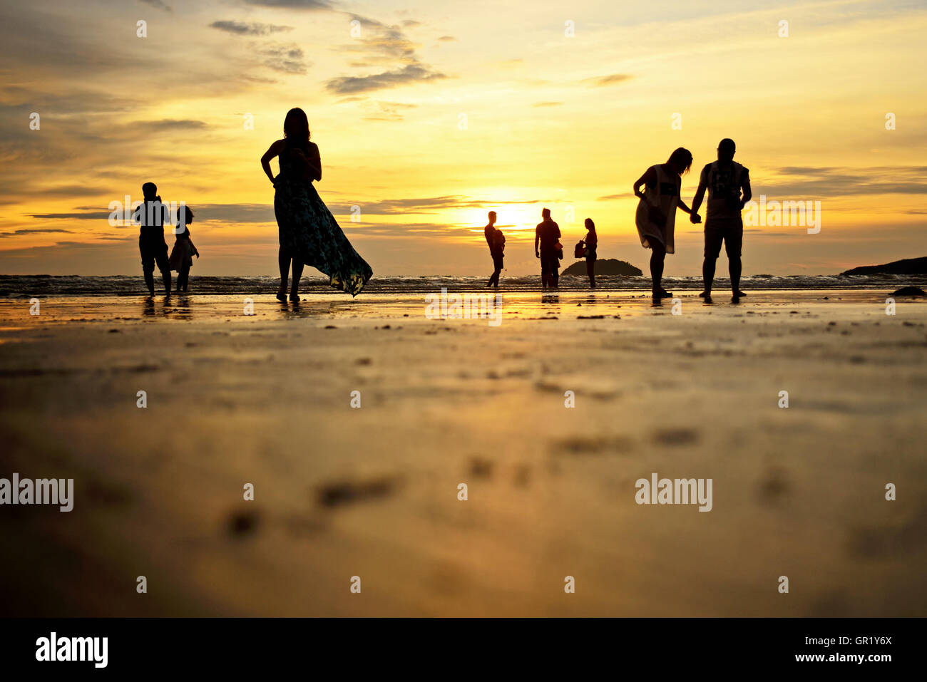 Low angle et selective focus shot de silhouettes d'amateurs de plage pour le coucher du soleil sur la plage de Tanjung Aru, Kota Kinabalu, Sabah. Banque D'Images
