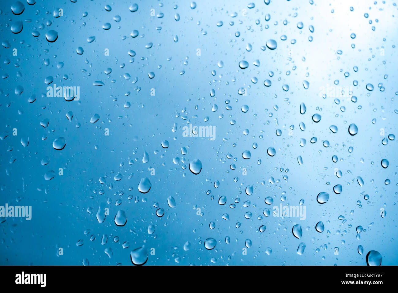 Des gouttelettes de pluie sur une fenêtre avec verre teinté bleu ciel Banque D'Images