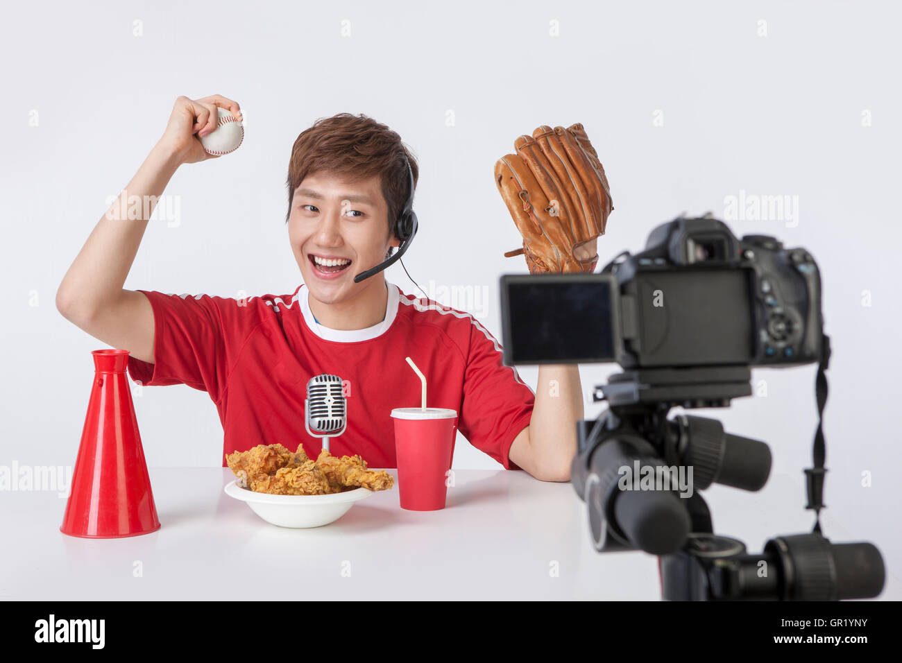 Portrait of young smiling man with baseball et de la nourriture sur table posing in front of camera Banque D'Images