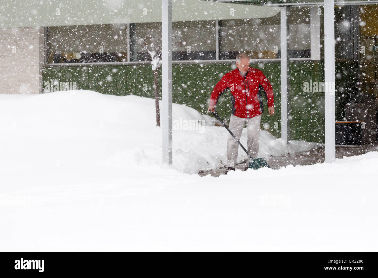 Homme de pelleter de la neige sur un trottoir durant une tempête de neige dans le Wisconsin. Banque D'Images