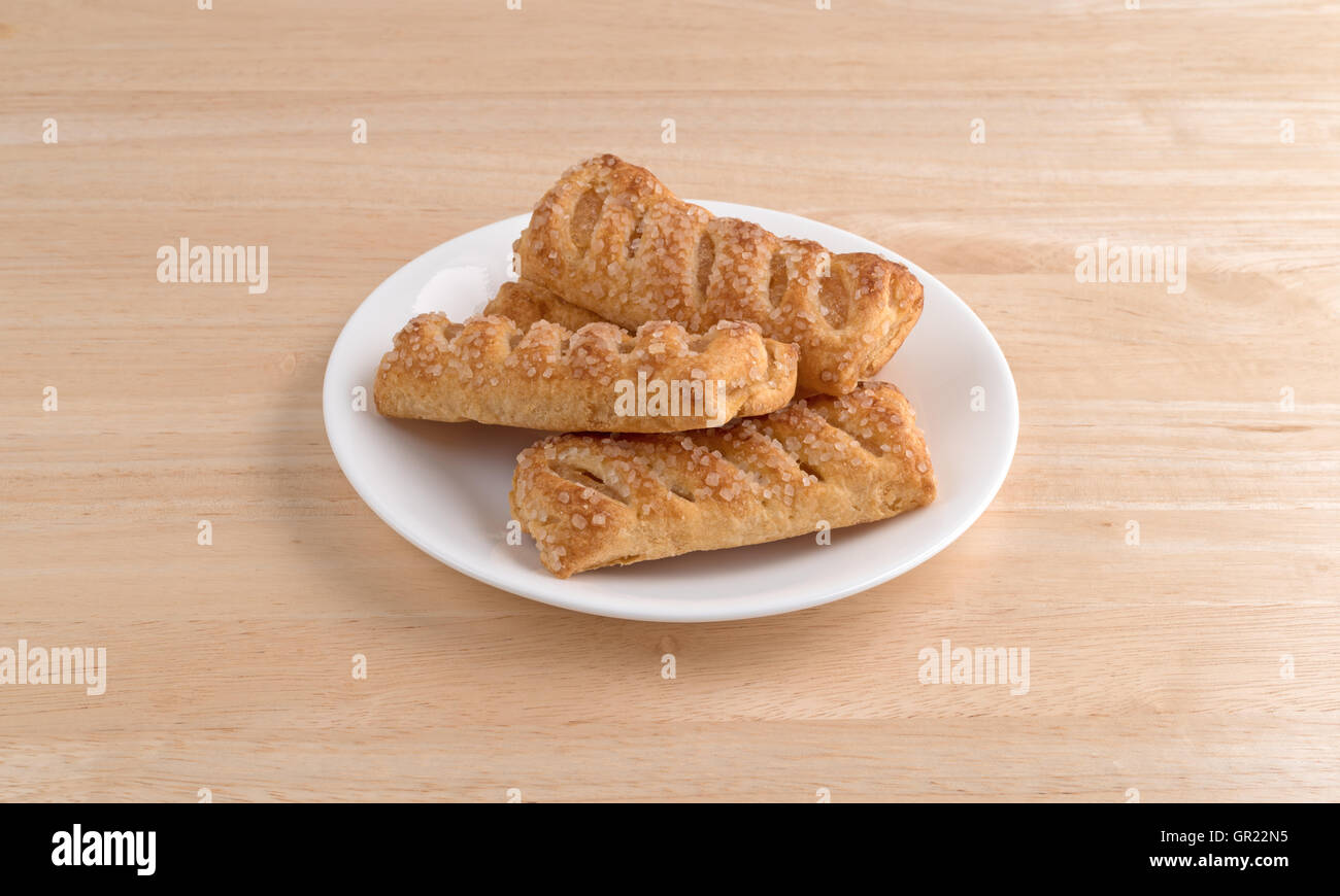 Plusieurs dragées aux tartes aux fruits apple sur une plaque blanche au sommet d'une table en bois. Banque D'Images