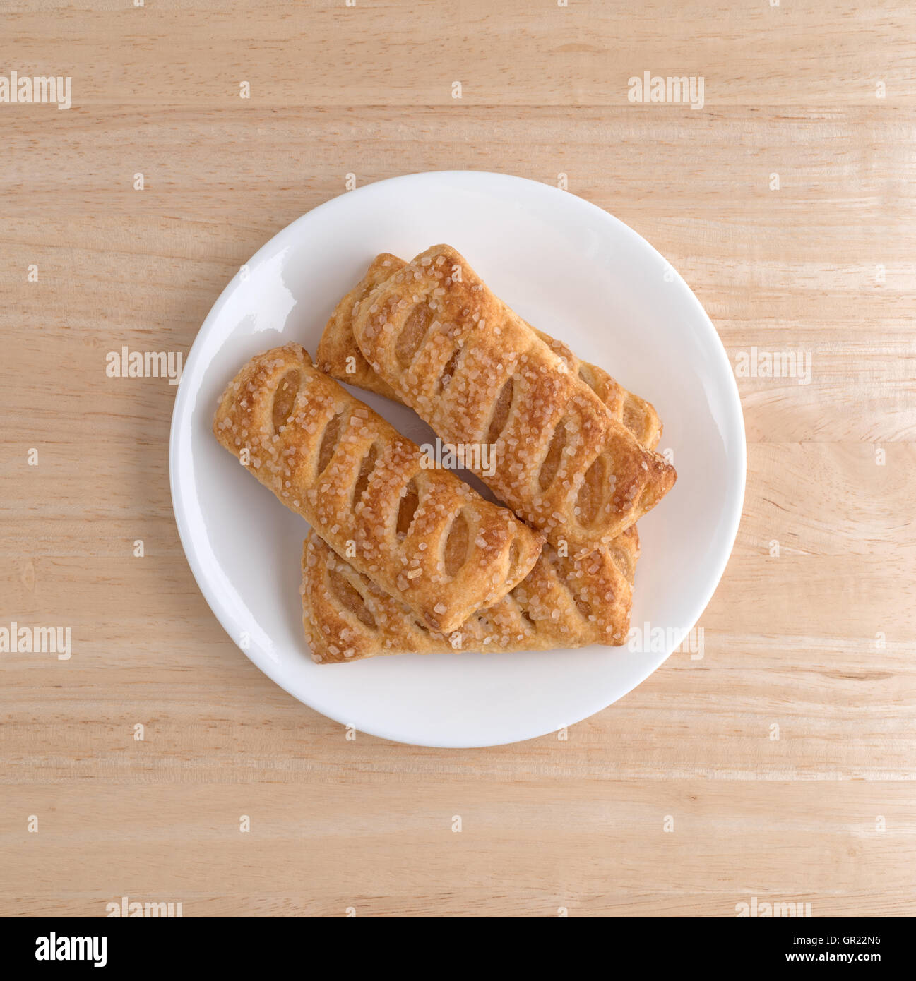 Vue de dessus de plusieurs dragées aux tartes aux fruits apple sur une plaque blanche au sommet d'une table en bois. Banque D'Images