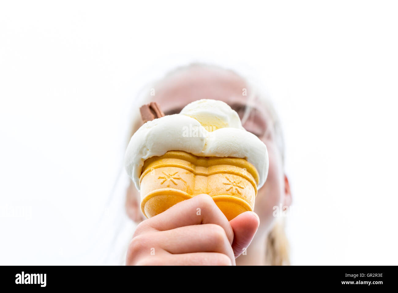 Une jeune fille jouit d'un cornet de crème glacée par une chaude journée d'été. Banque D'Images