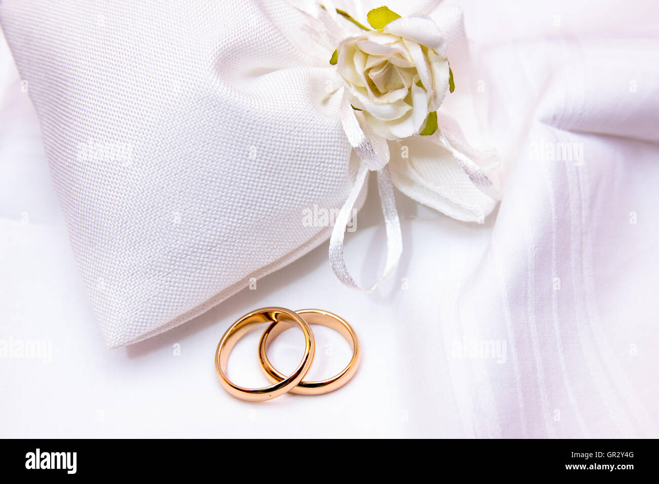 Les anneaux de mariage dans un sac en tissu blanc avec des fleurs Banque D'Images