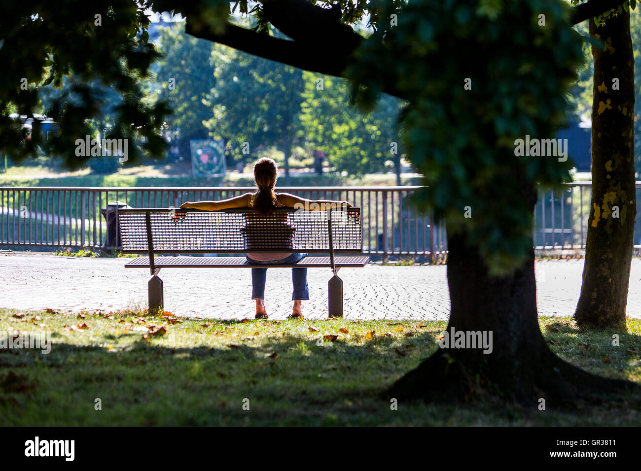 Jeune femme détendue, se détendre sur un banc de parc au soleil, Banque D'Images