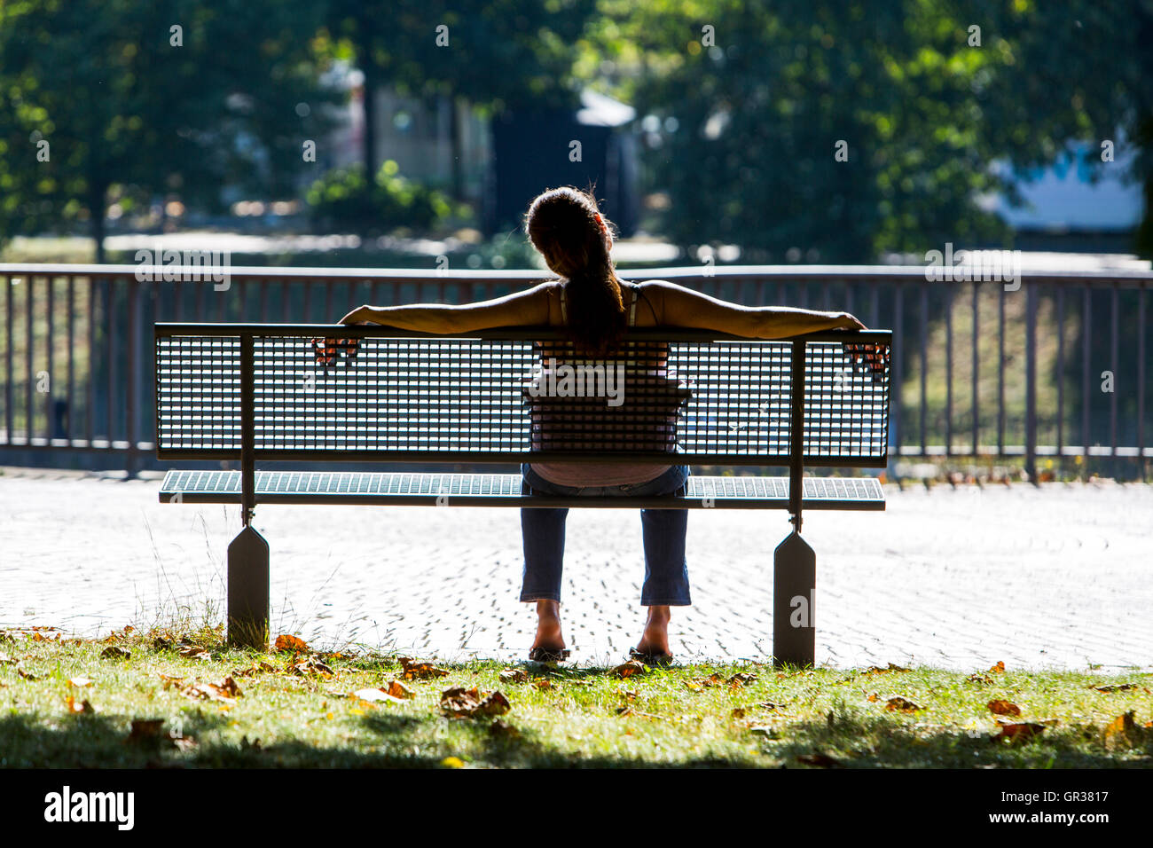 Jeune femme détendue, se détendre sur un banc de parc au soleil, Banque D'Images