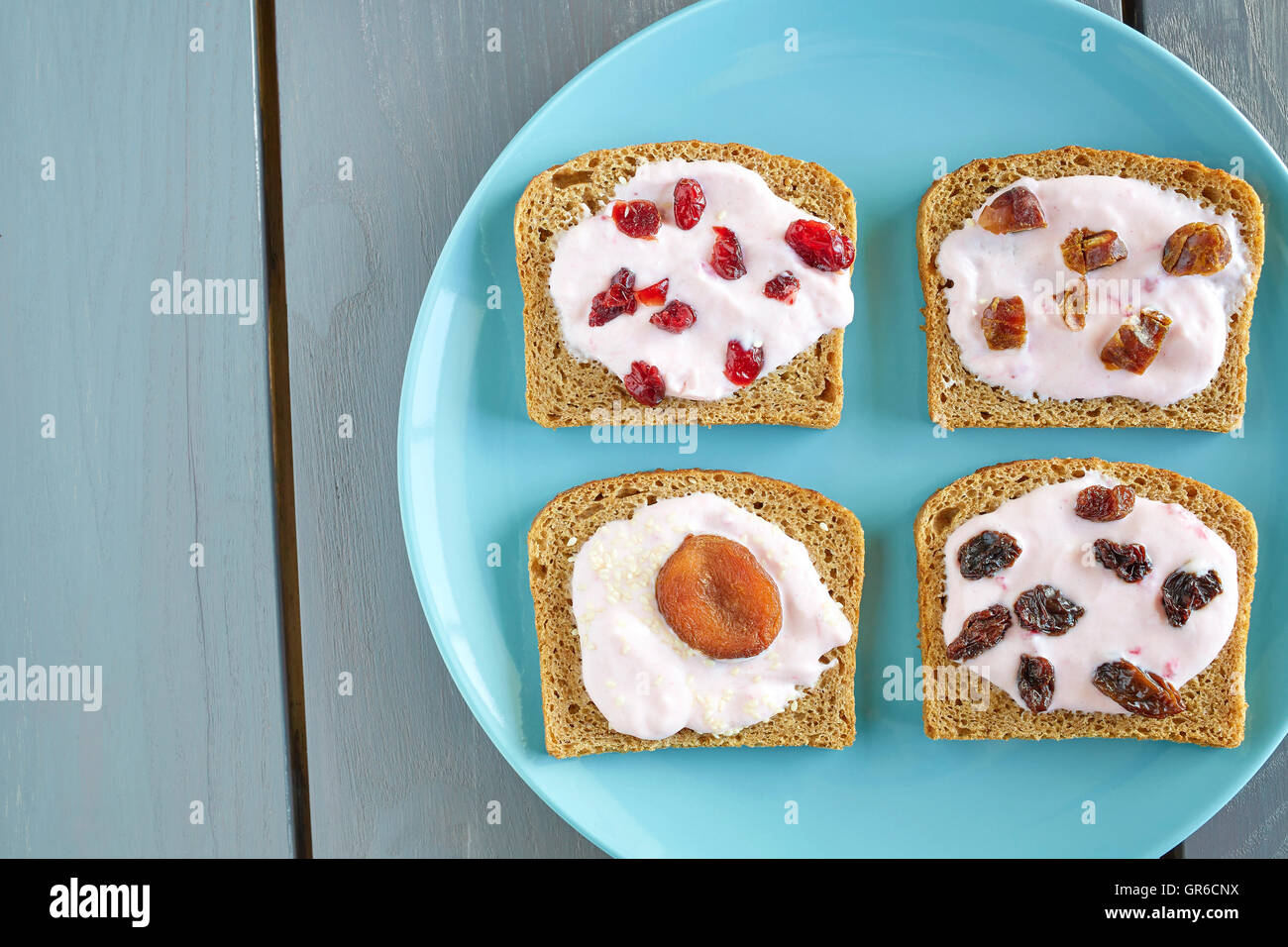 Du pain avec du fromage à la crème aux fraises et fruits secs sur plaque bleue, petit-déjeuner sain de réglage ci-dessus. Banque D'Images