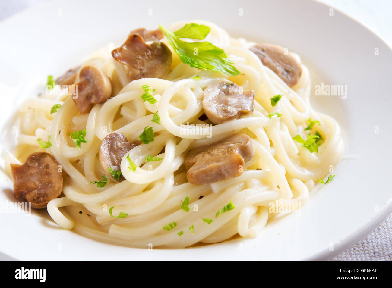 Les pâtes Spaghetti aux champignons grillés et verts sur plaque blanche close up Banque D'Images