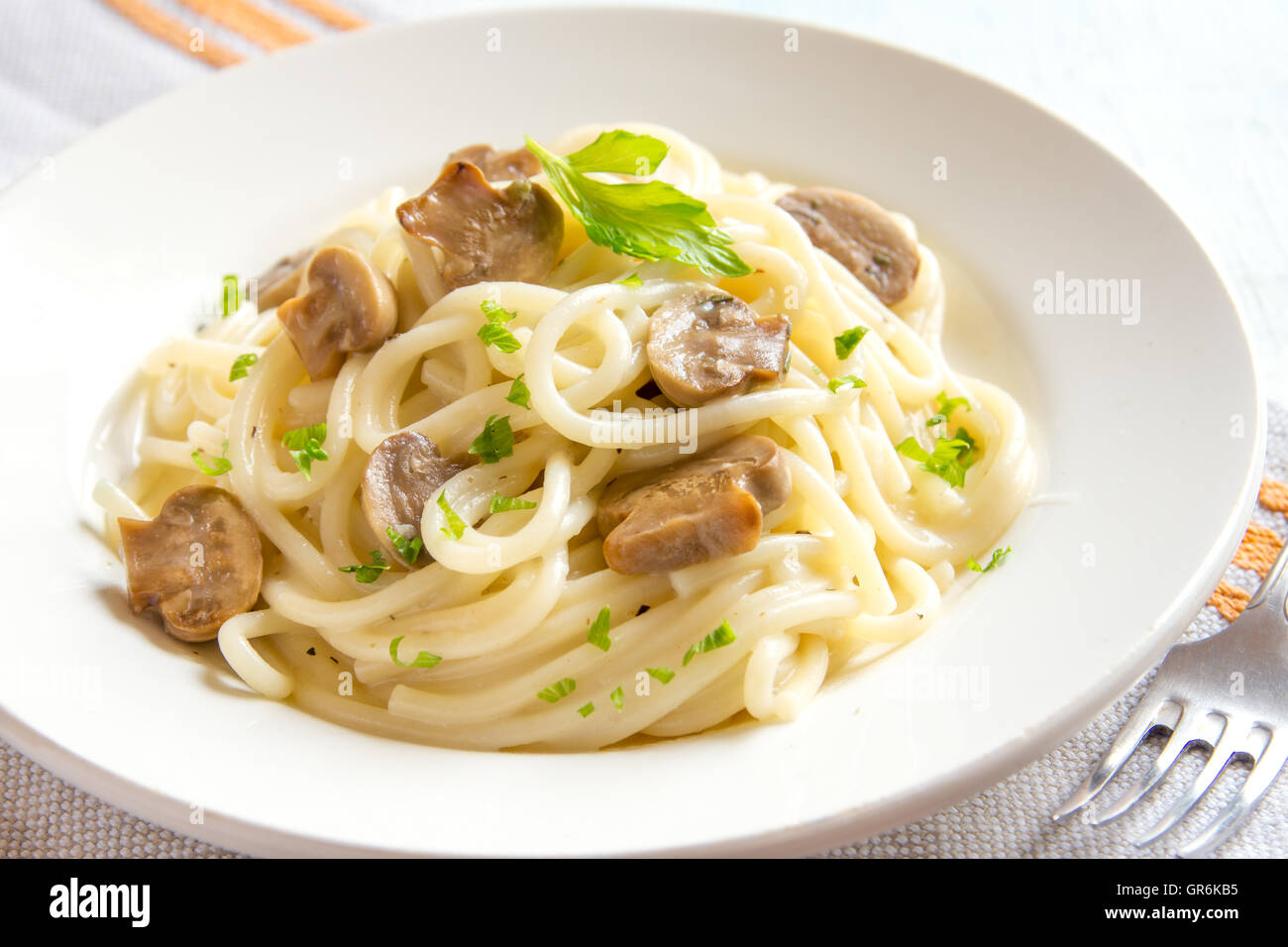 Les pâtes Spaghetti aux champignons grillés et verts sur plaque blanche