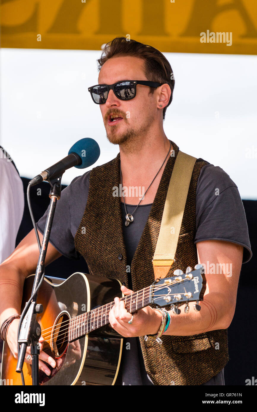 Broadstairs folk semaine. Jeune homme guitariste chanteur folklorique, portant des lunettes de soleil, un spectacle dans le kiosque. Close up de singer et de la guitare. Banque D'Images