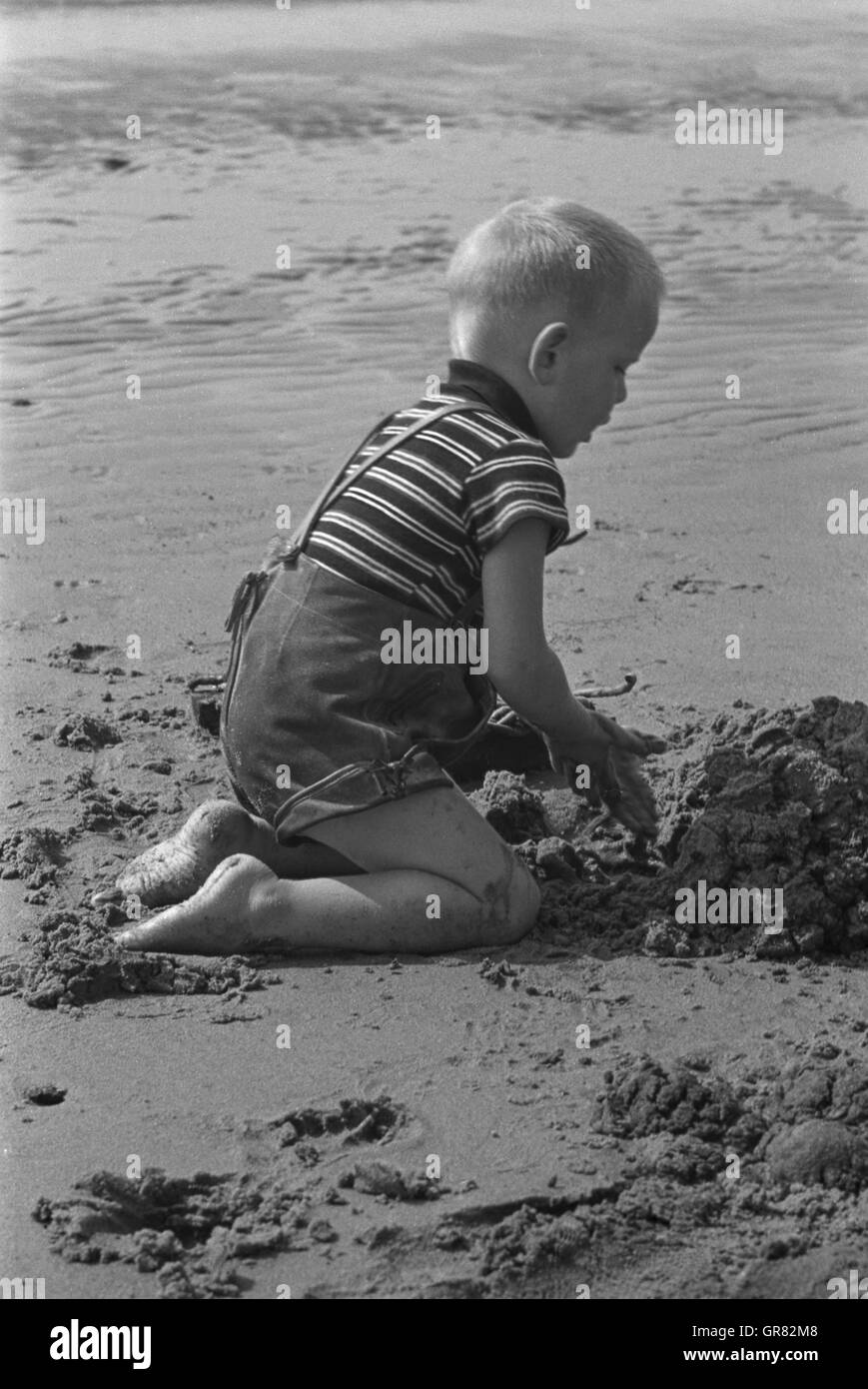 Enfant jouant dans le sable 1970 P.C. Banque D'Images