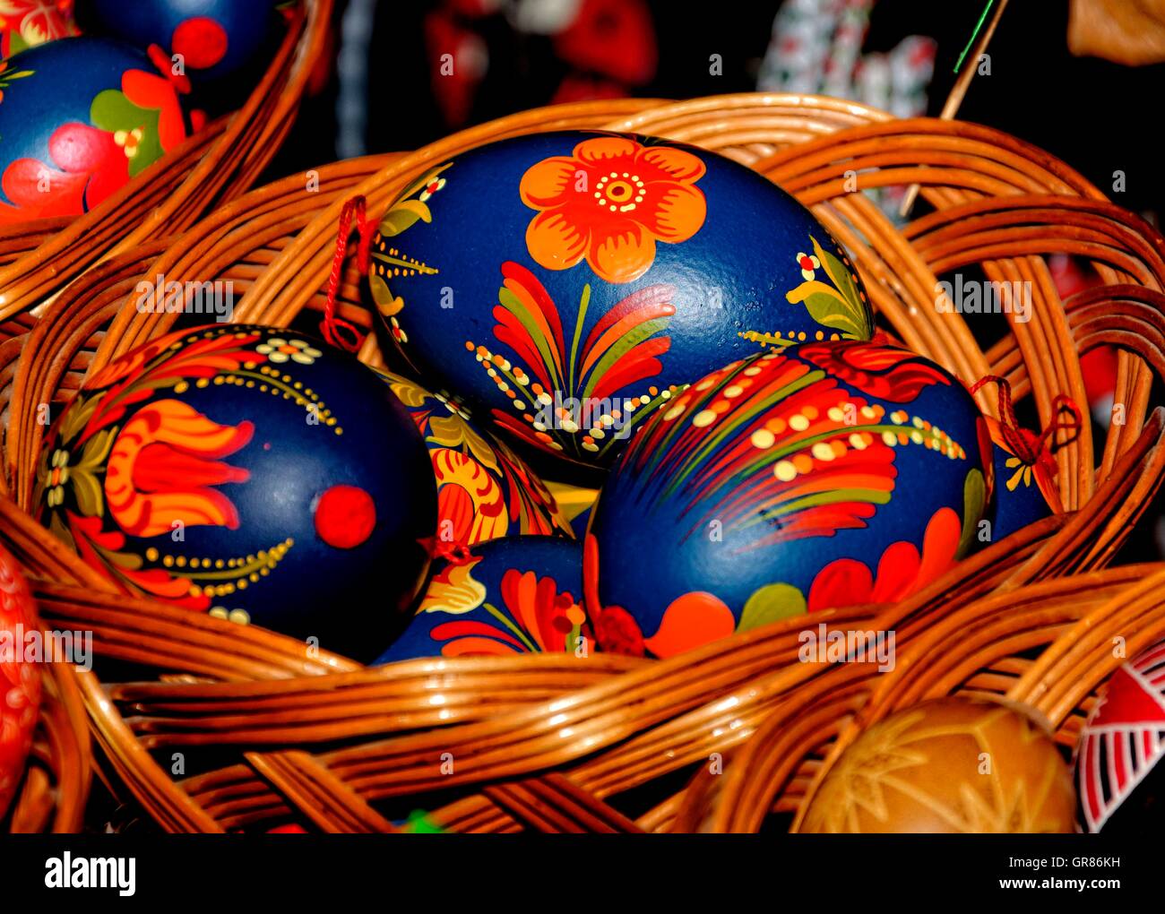 Les oeufs de Pâques peints en bleu avec des fleurs orange rouge dans Panier Banque D'Images