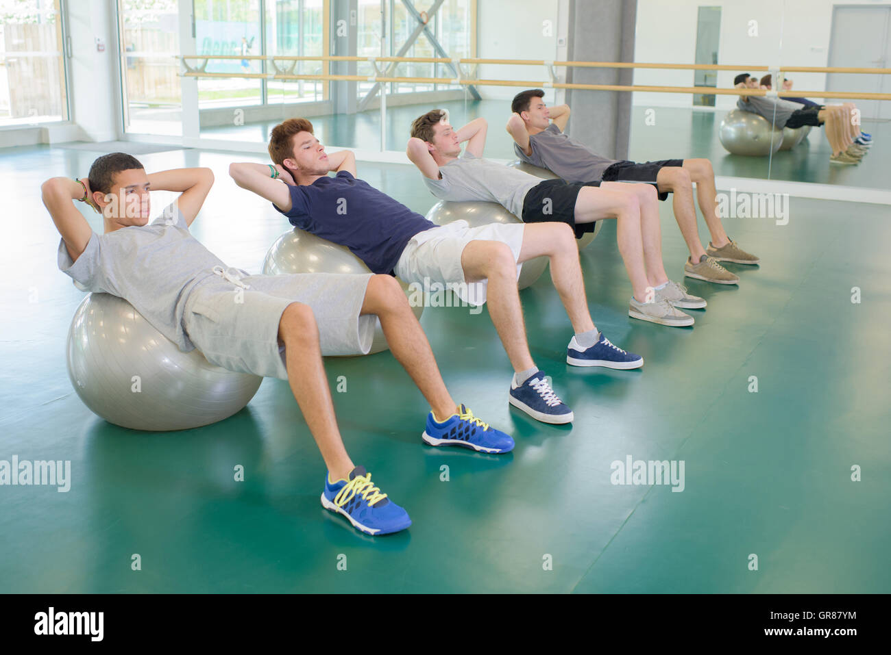 Quatre hommes l'exercice aérobique sur balls Banque D'Images
