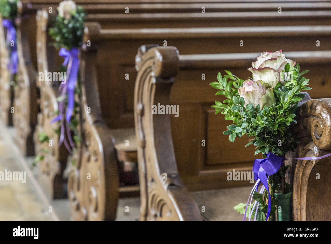 Vue détaillée d'un vieux banc de bois dans une église avec une décoration florale Banque D'Images