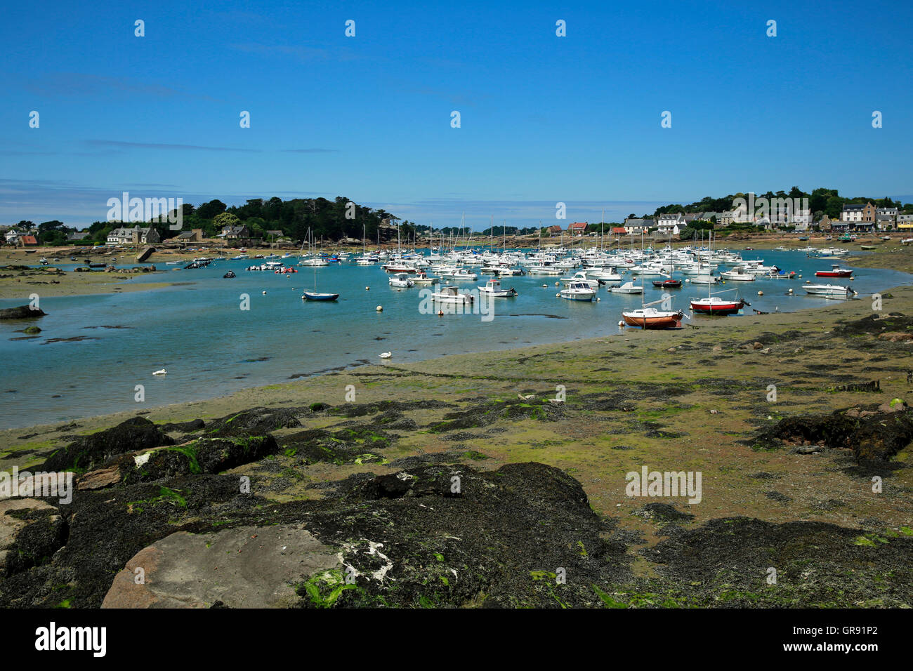 Bateaux dans une baie à marée basse à Ploumanach, Bretagne, France Banque D'Images