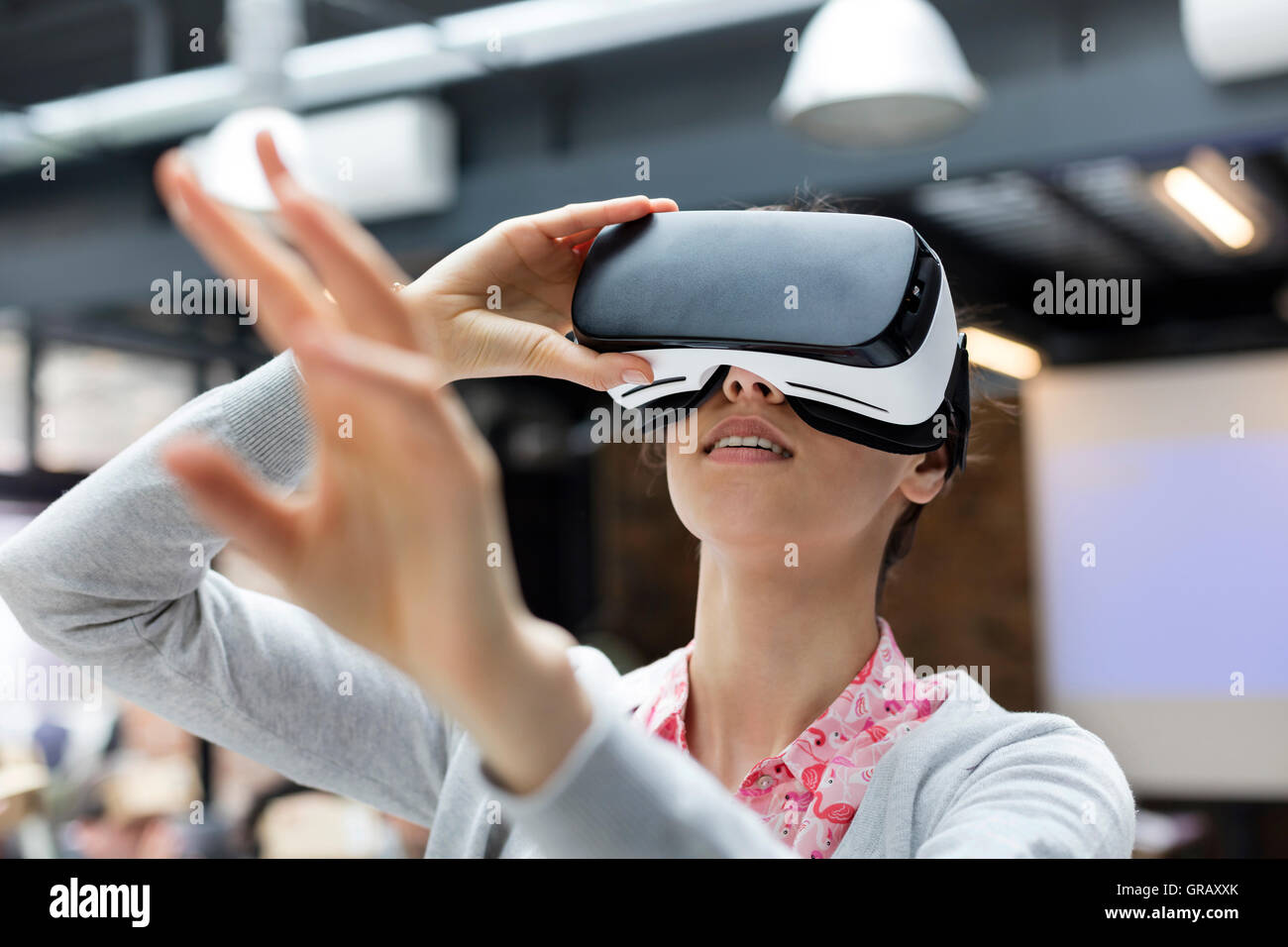 Femme essayant simulateur de réalité virtuelle lunettes lunettes atteindre Banque D'Images