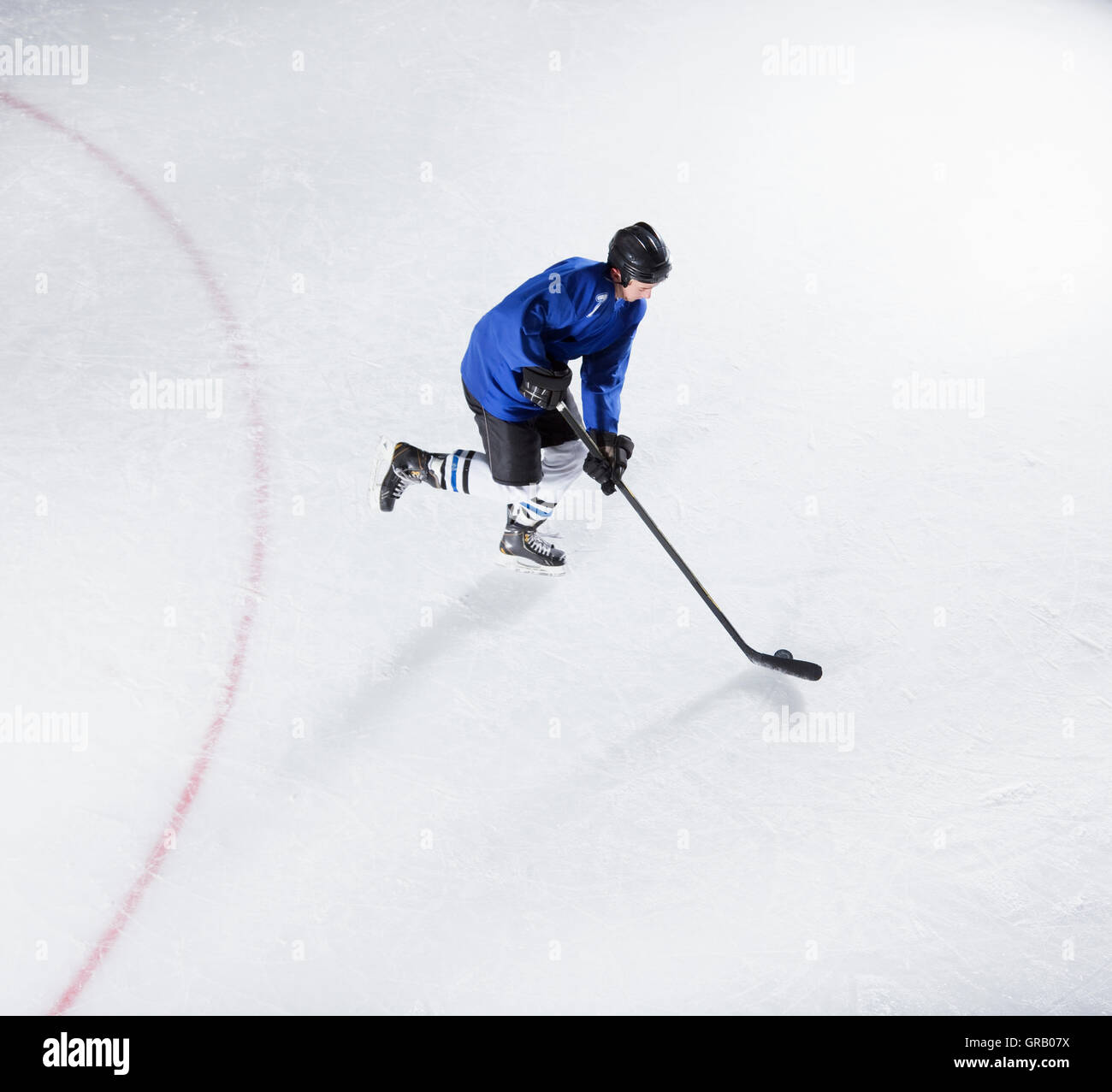 Le joueur de hockey en uniforme bleu avec rondelle de patinage sur glace Banque D'Images