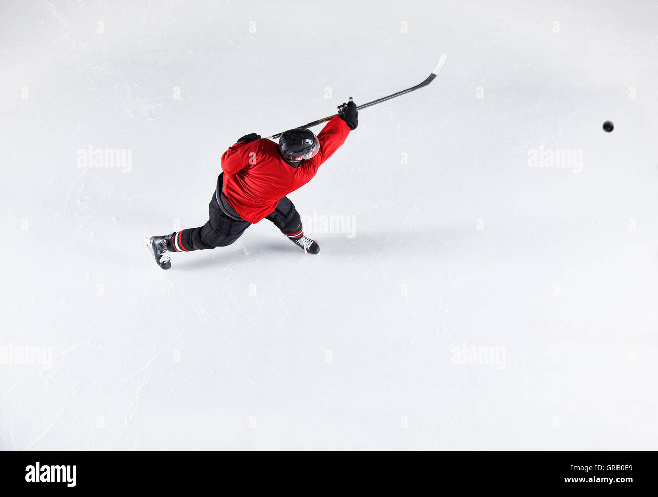 Le joueur de hockey en uniforme rouge sur la glace palet de tir Banque D'Images