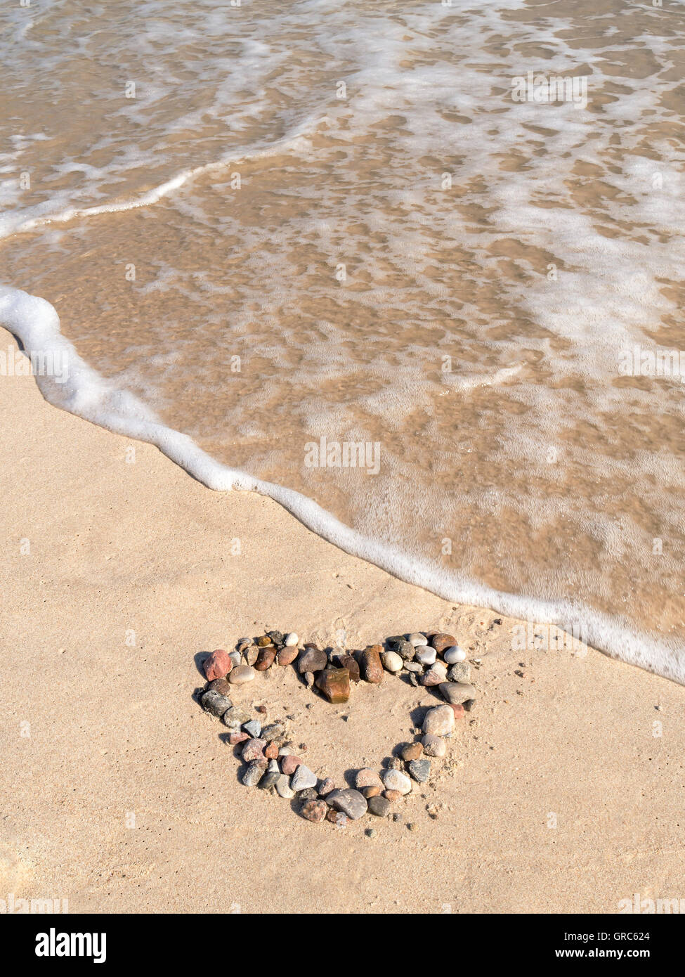 Signe du cœur organisé à partir de galets sur le sable de la plage Banque D'Images