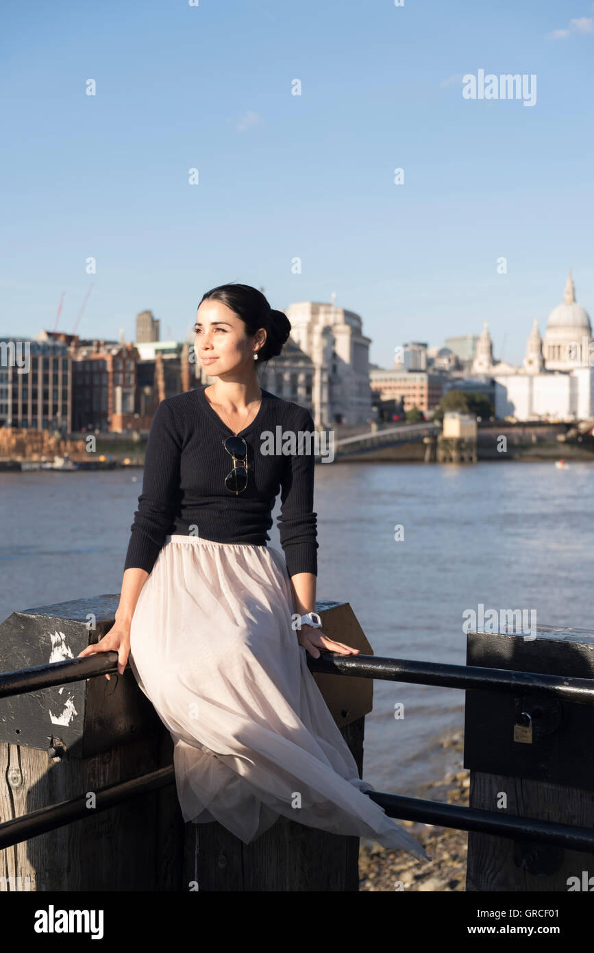 Femme assise à côté de Tamise, avec la Cathédrale St Paul à l'arrière-plan. Londres, Angleterre Banque D'Images