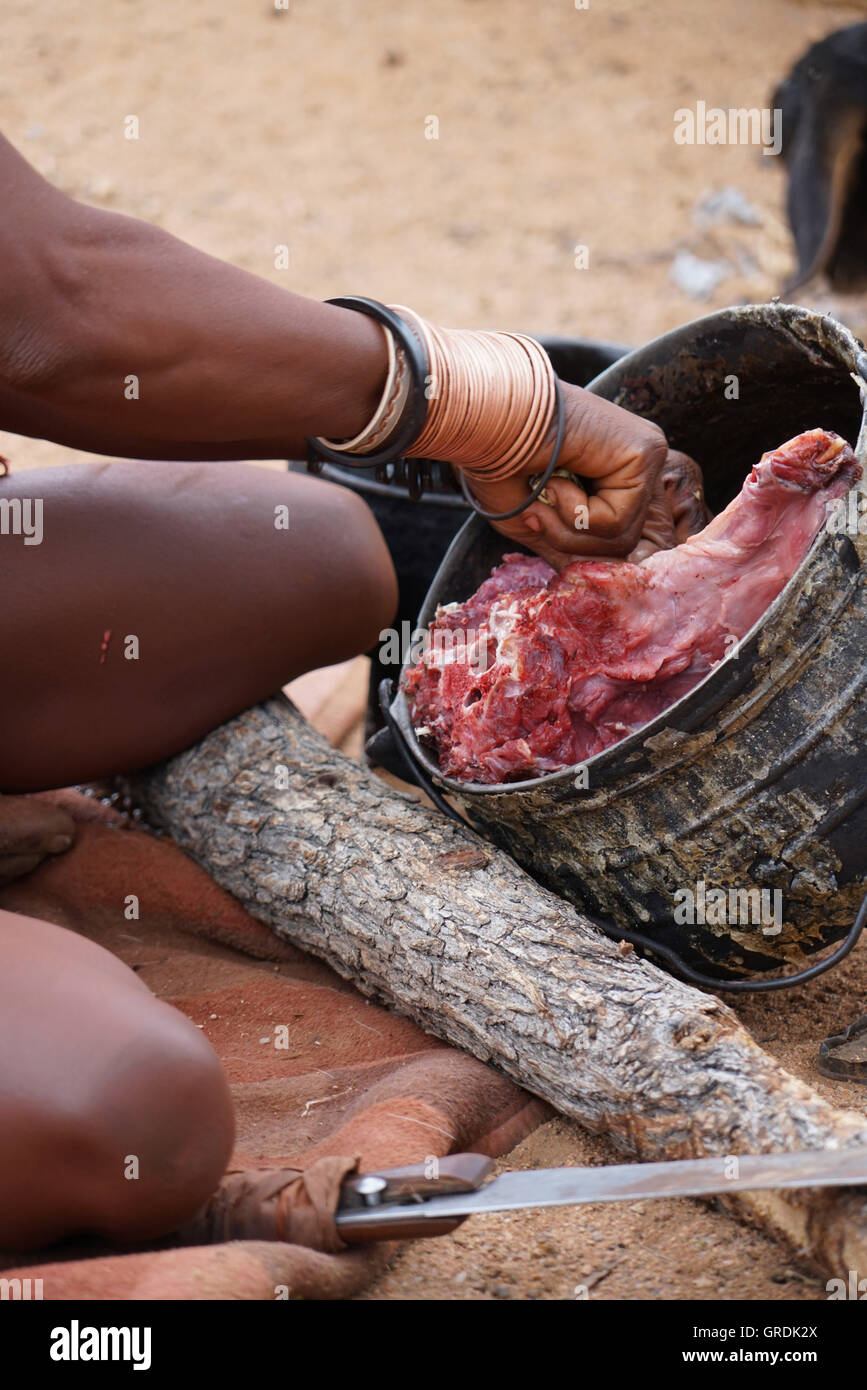 Femme Himba coupe la viande, prépare la nourriture, la Namibie, l'Afrique Banque D'Images
