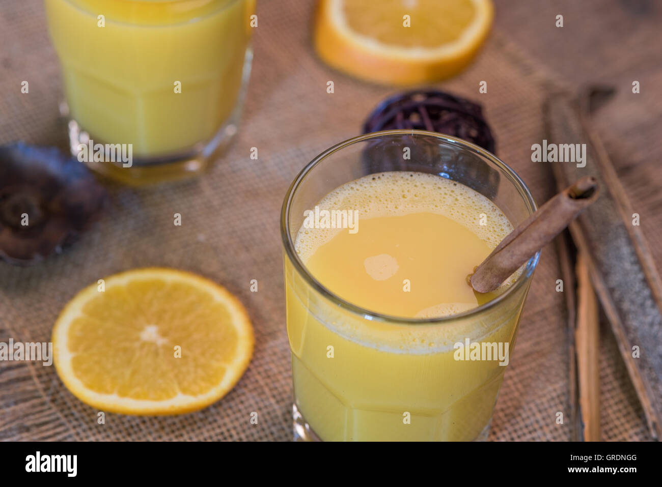 Verre de jus d'orange rustique avec des herbes séchées et les rondelles d'oranges sur jute Banque D'Images