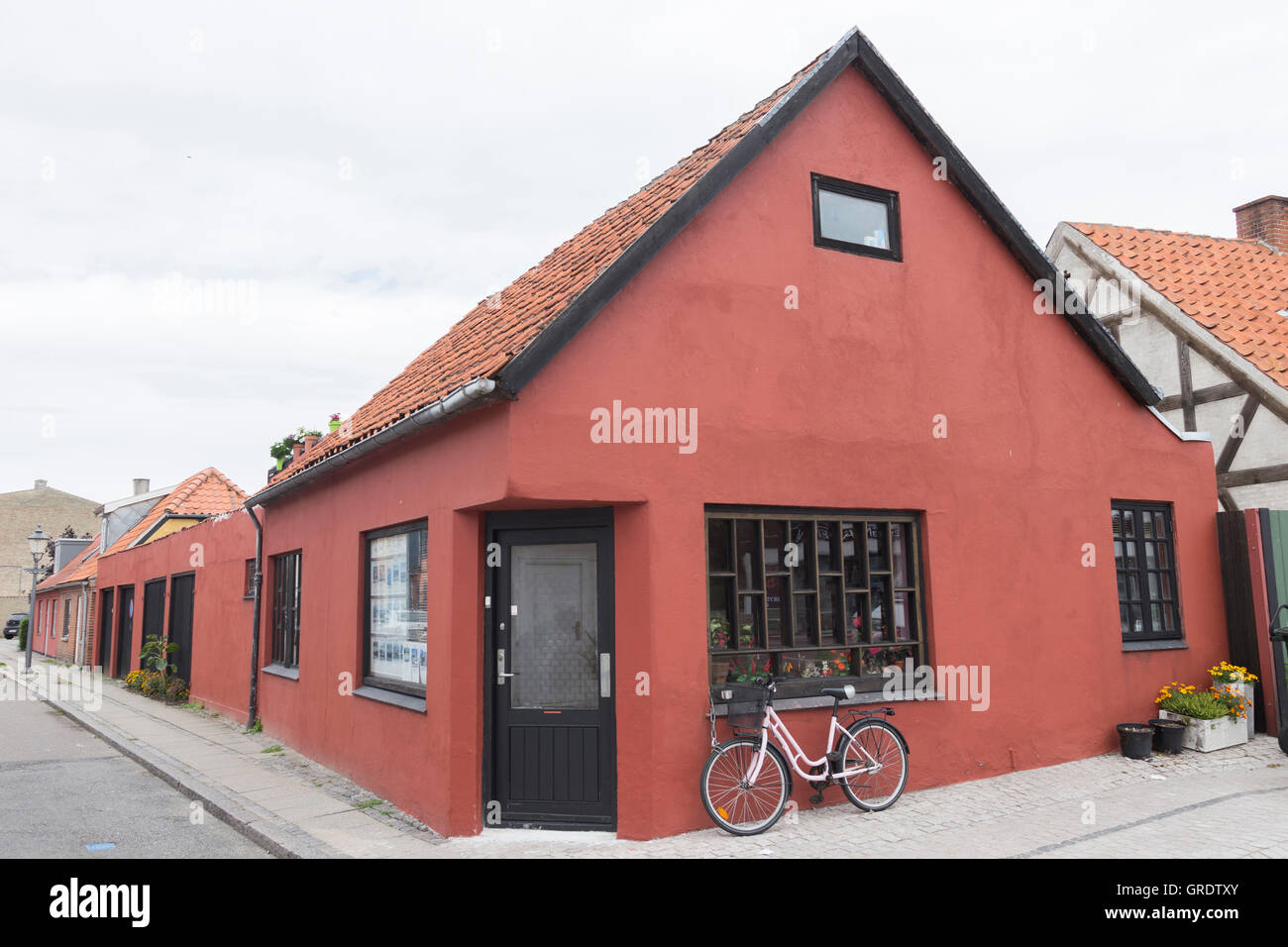 Red Corner House en Nykobing avec une petite boutique et un vélo à l'avant Banque D'Images