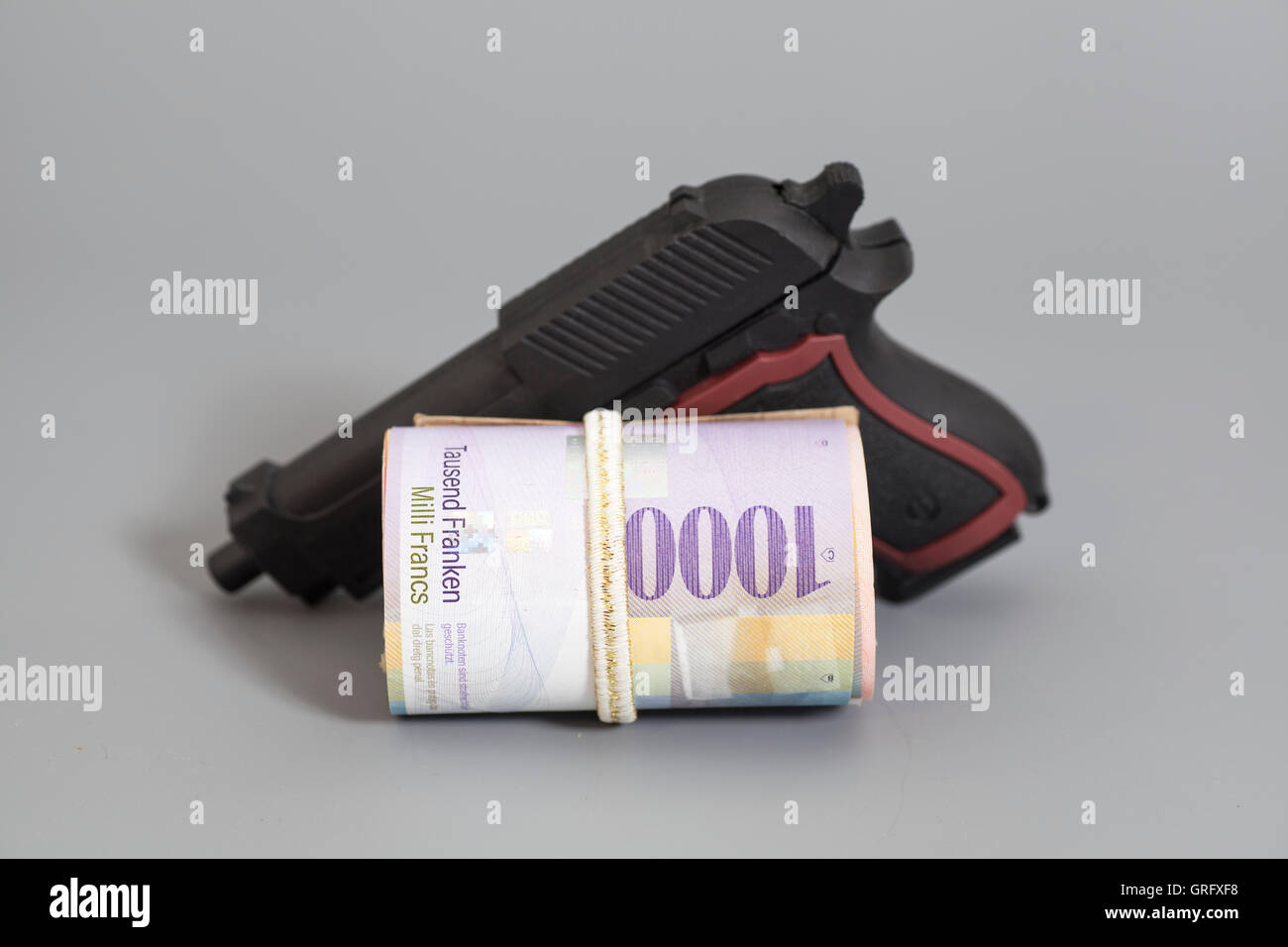 Mille francs suisses dans un rouleau, pistolet et fond gris Banque D'Images