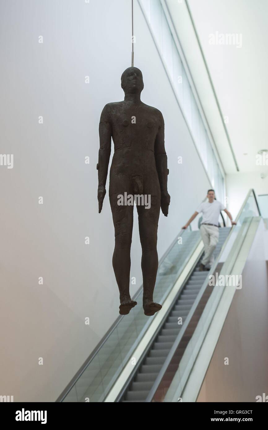 Antony Gormley se déplace sur un escalator passé une sculpture grandeur nature de l'objet lui-même - 1999 - qui est suspendu au plafond sur l'aile Ondaatje Hall principal de la National Portrait Gallery, Londres. Banque D'Images