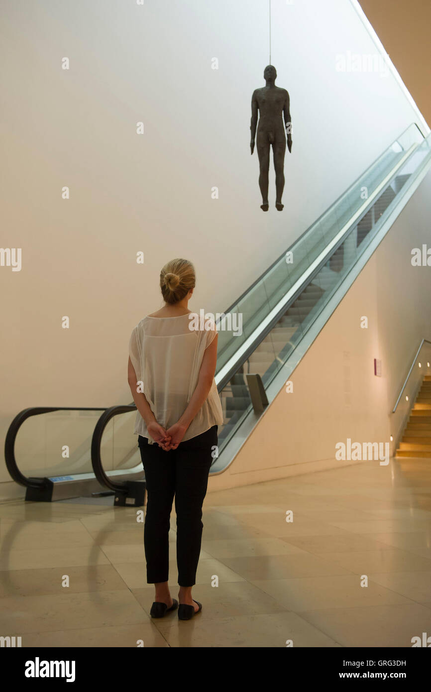 Une femme regarde une sculpture grandeur nature d'Antony Gormley - Objet, 1999 - qui est suspendu au plafond sur l'aile Ondaatje Hall principal de la National Portrait Gallery, Londres. Banque D'Images