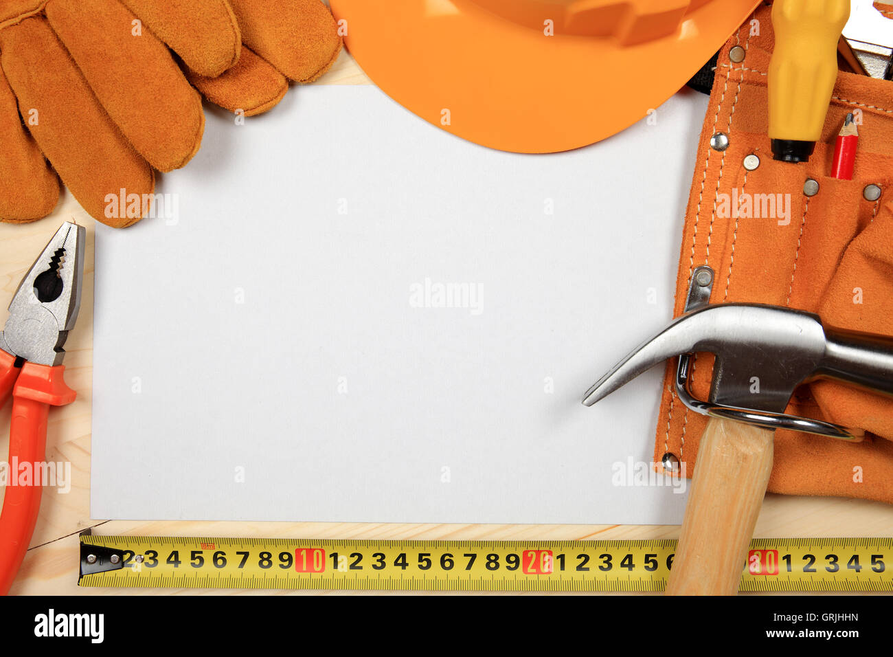 Hard Hat, marteau, pinces, clous, crayon rouge, gants de travail et d'autres outils isolé sur un fond de bois avec une feuille de p Banque D'Images
