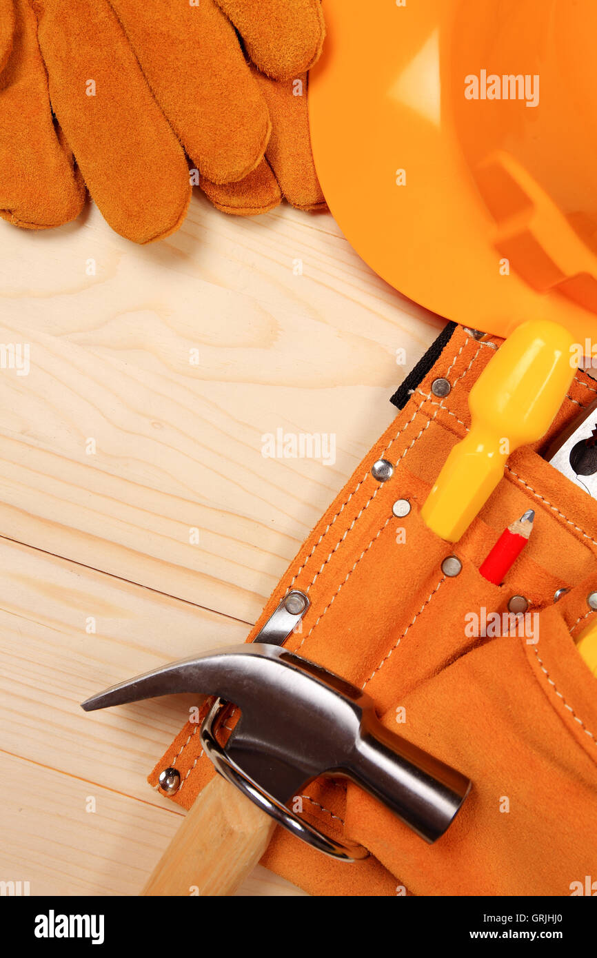 Marteau, pinces, casque, crayon rouge, gants de travail et d'autres outils isolé sur un fond de bois Banque D'Images