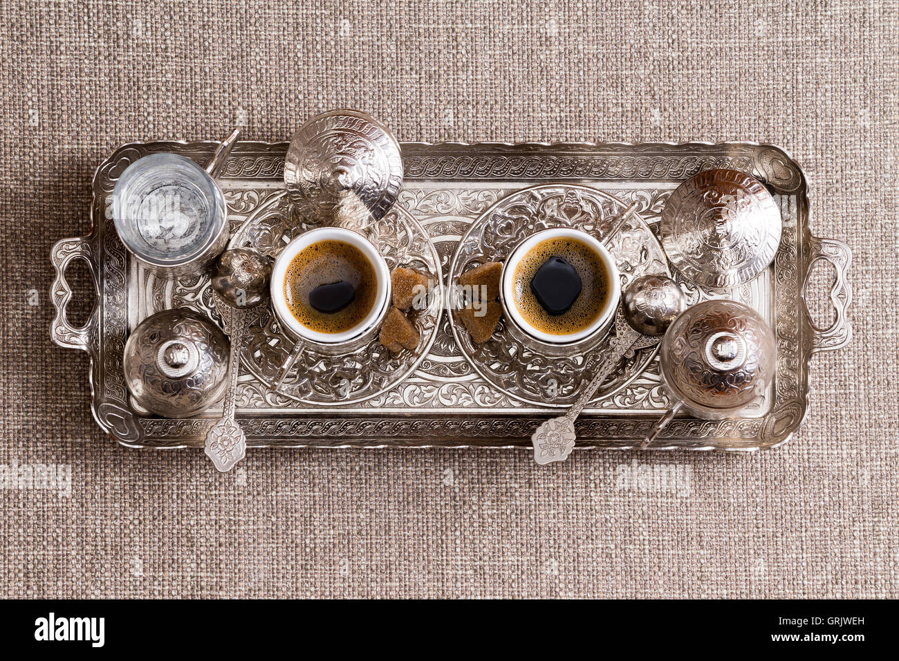 Ornements traditionnels le plateau métallique avec deux tasses de café turc fraîchement infusé avec du sucre, des disques et un pot ou cezve vue Banque D'Images