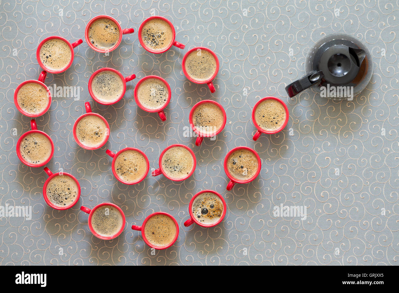 Spirale hélicoïdale ou décoratifs de café noir moussé fraîchement coulé en rouge les tasses avec un plein pot de café à la fin comme tu Banque D'Images