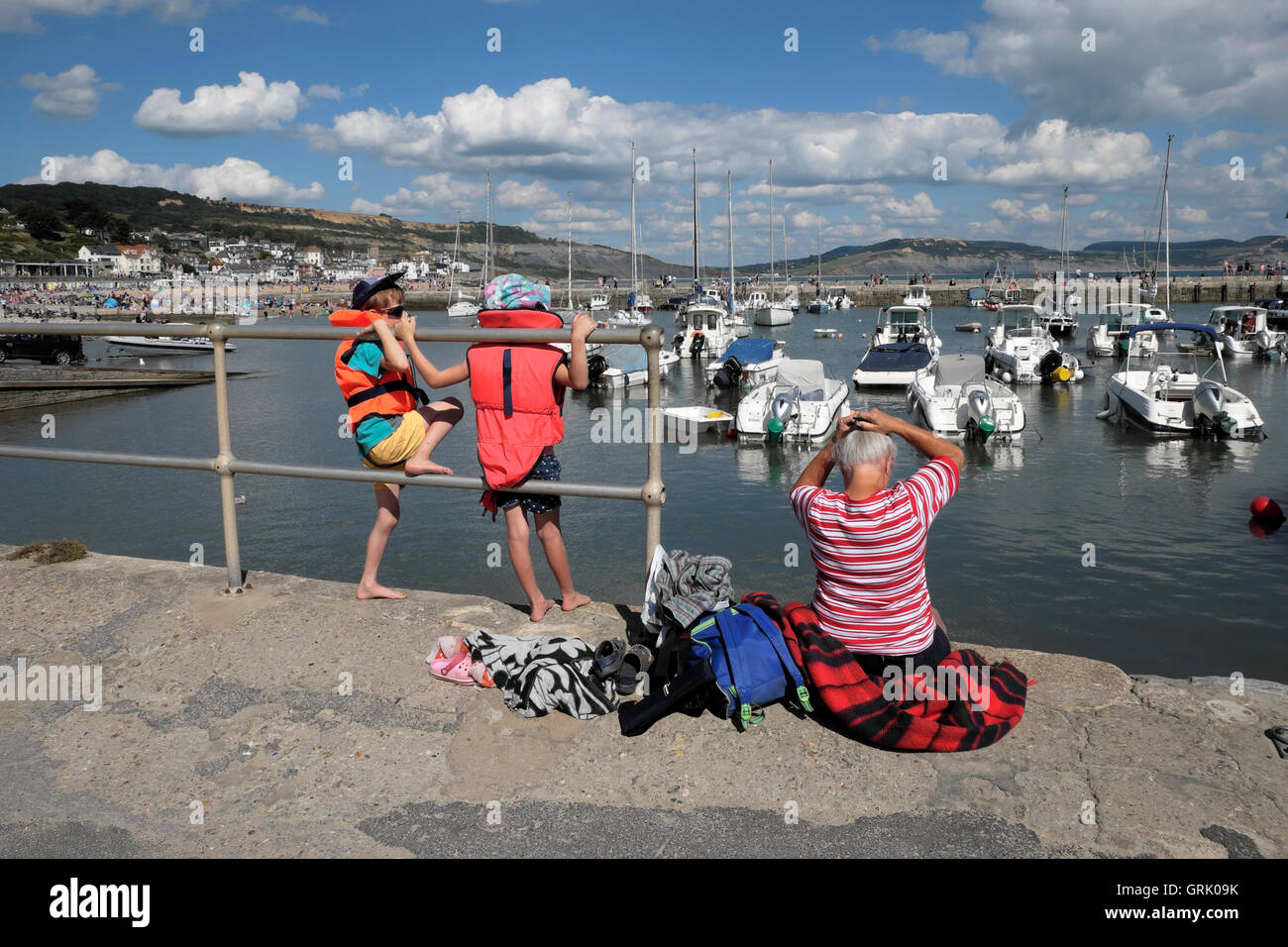Une grand-mère et deux petits-enfants s'asseoir sur le quai du port le long de la Cobb à Lyme Regis Dorset England UK KATHY DEWITT Banque D'Images