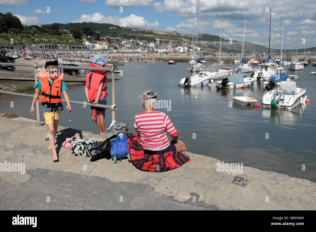 Une grand-mère et deux petits-enfants s'asseoir sur le quai du port le long de la Cobb à Lyme Regis Dorset England UK KATHY DEWITT Banque D'Images