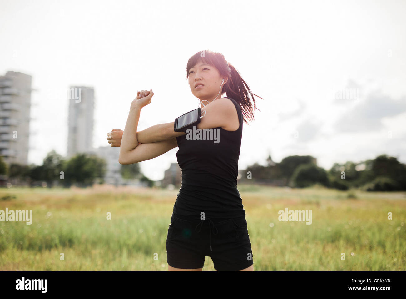 Shot de fit young woman stretching au parc urbain. Modèle féminin chinois dans les vêtements de sport faisant réchauffer l'exercice dans un parc à matin Banque D'Images