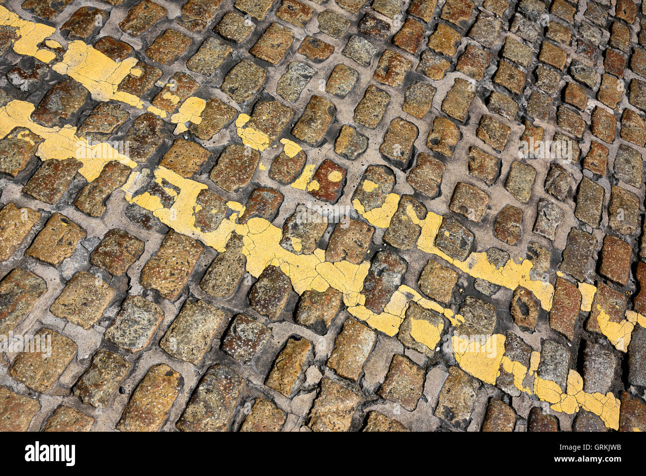 Les lignes jaunes double sur cobble stones Banque D'Images