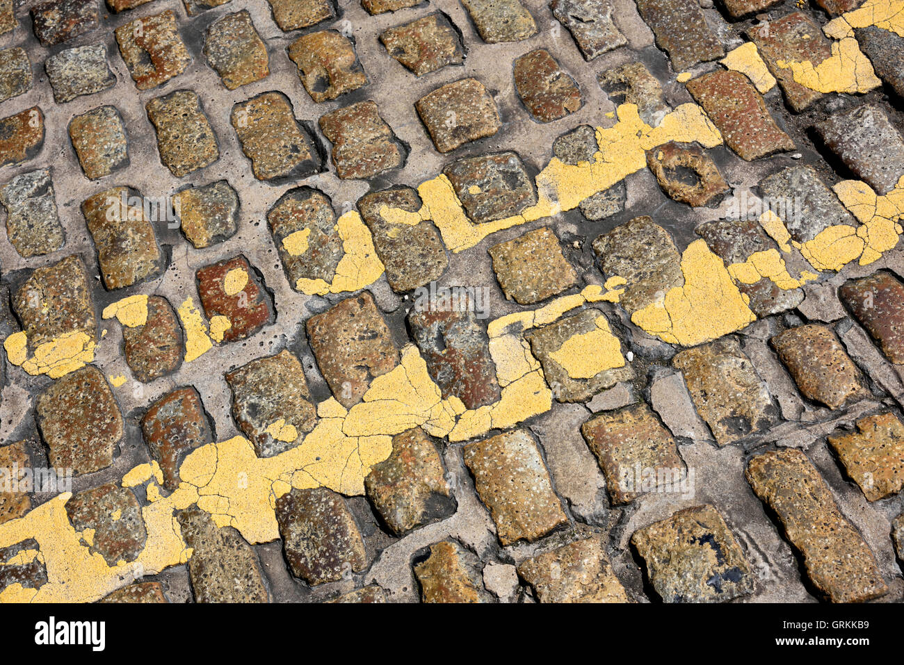 Les lignes jaunes double sur cobble stones Banque D'Images