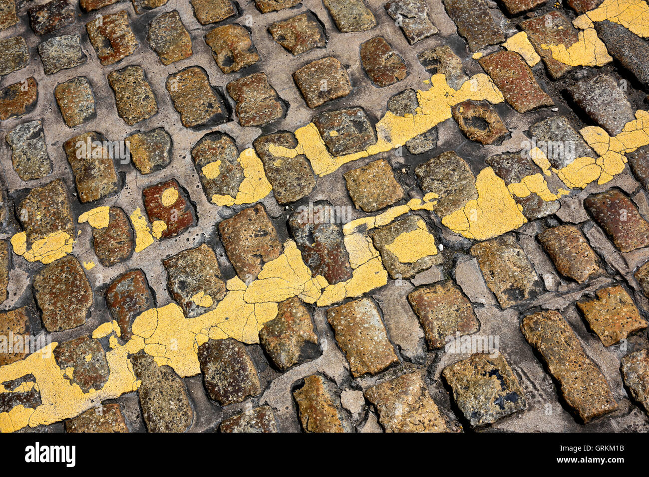 Les lignes jaunes double sur cobble stones Banque D'Images