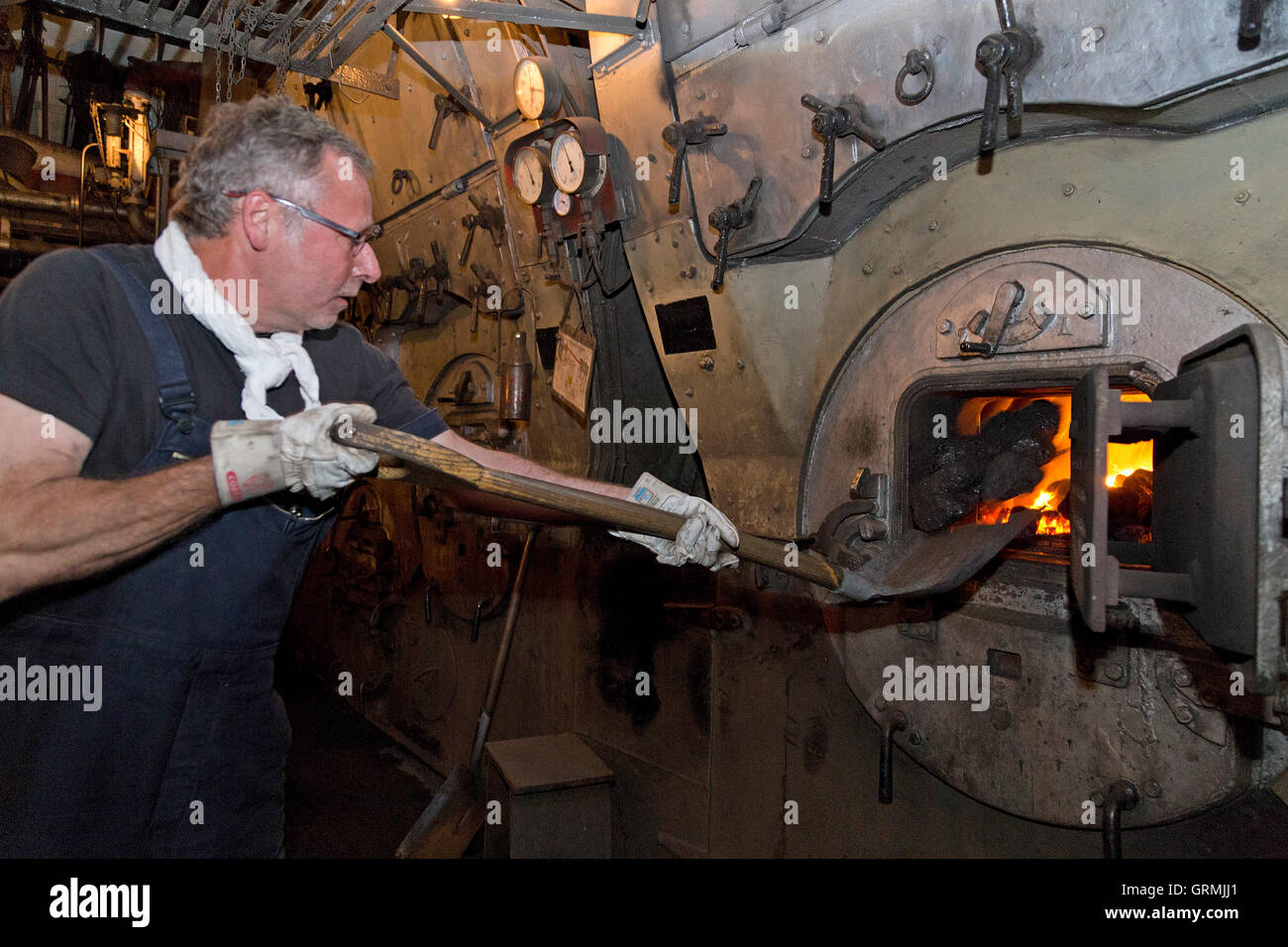 Stoker à pelleter du charbon dans la chaudière à vapeur 'Stettin, brise-glace' sur sa façon de Hambourg à Kiel, Schleswig-Holstein, Allemagne Banque D'Images
