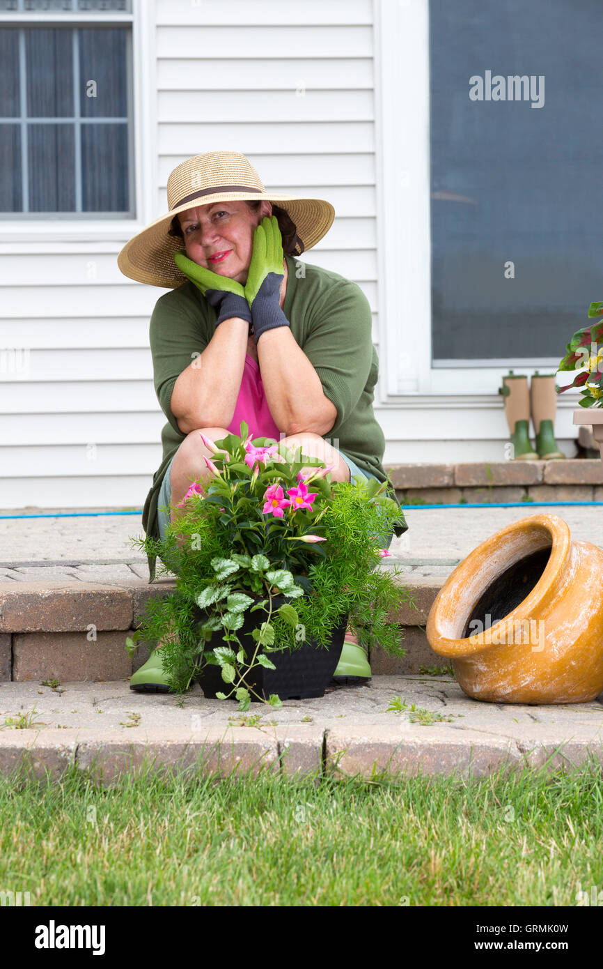 Grand-mère élégante dans les endurants et chapeau assis sur les étapes de  brique de son patio à l'air songeur à l'appareil photo avec un beau langage  SMIL Photo Stock - Alamy