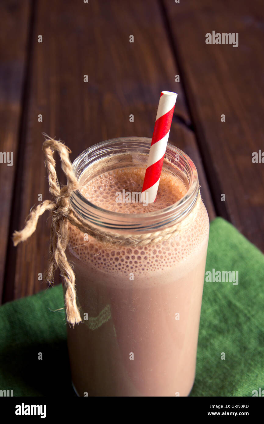 Smoothie chocolat (milkshake) avec de la paille dans le bocal sur la table en bois foncé Banque D'Images