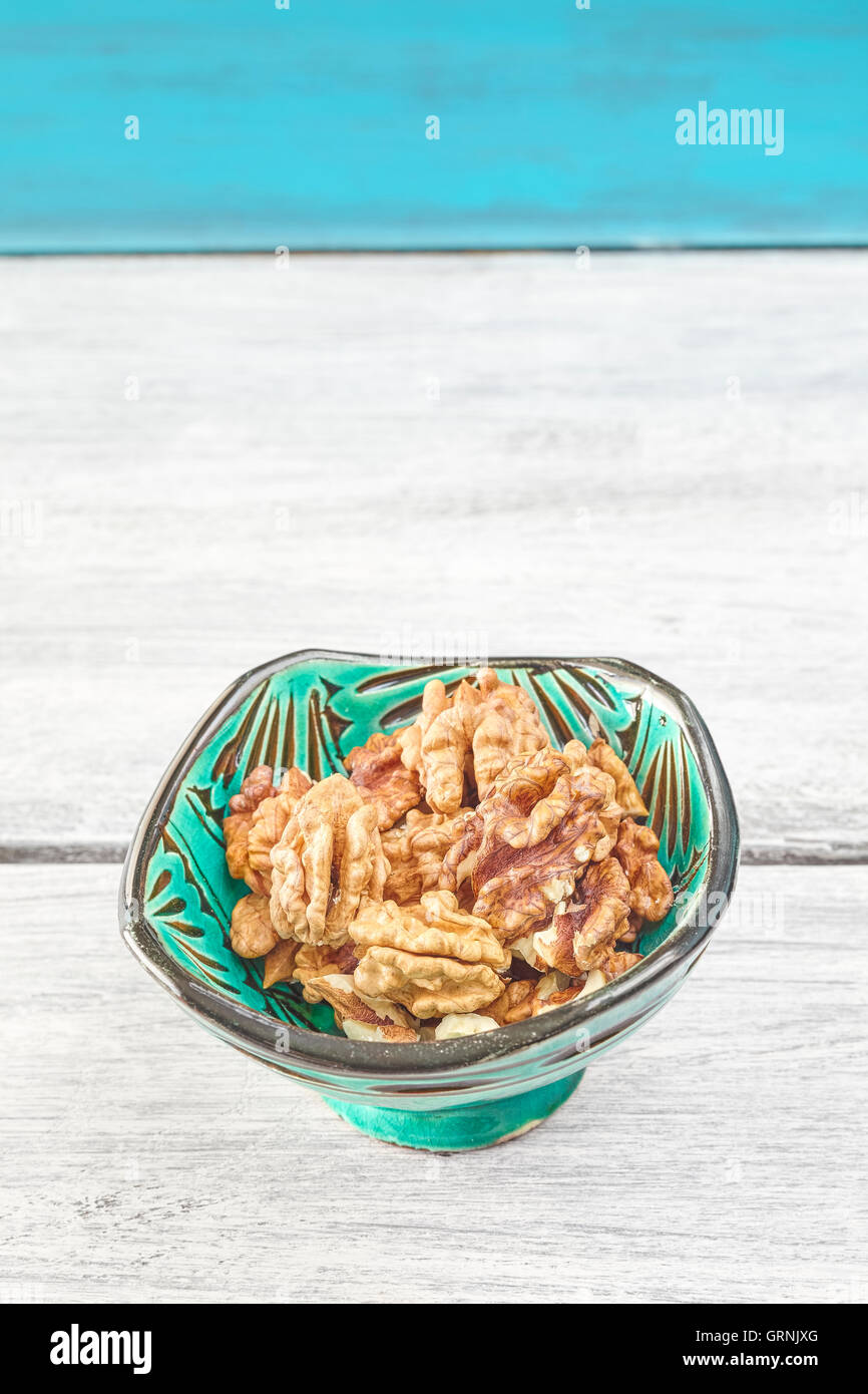 Les noix dans un bol vert sur une table rustique, de l'espace pour le texte. Banque D'Images