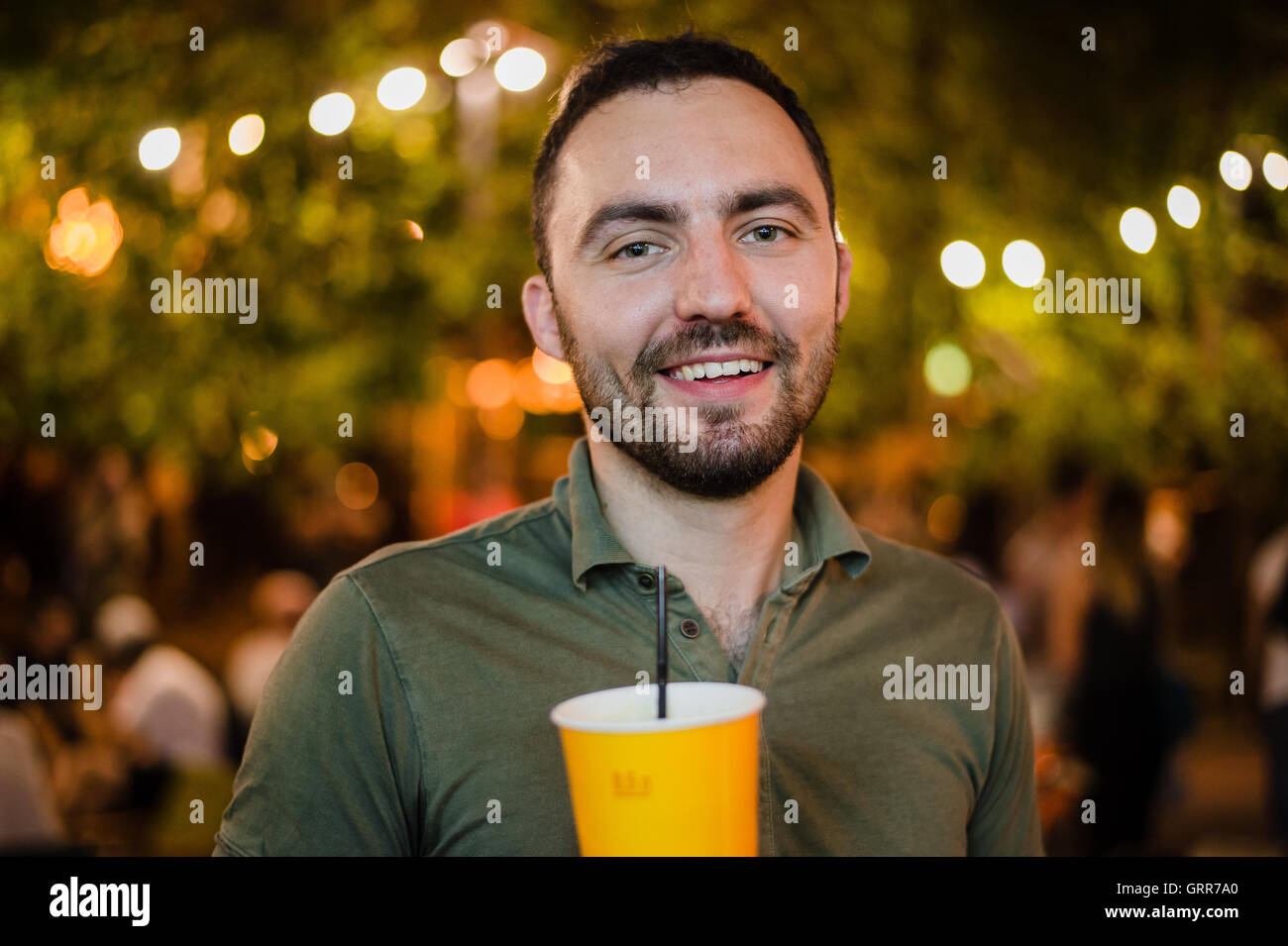 L'Homme barbu beau coctail potable ou de la bière en plein air au Café de la rue la nuit de la partie in park Banque D'Images