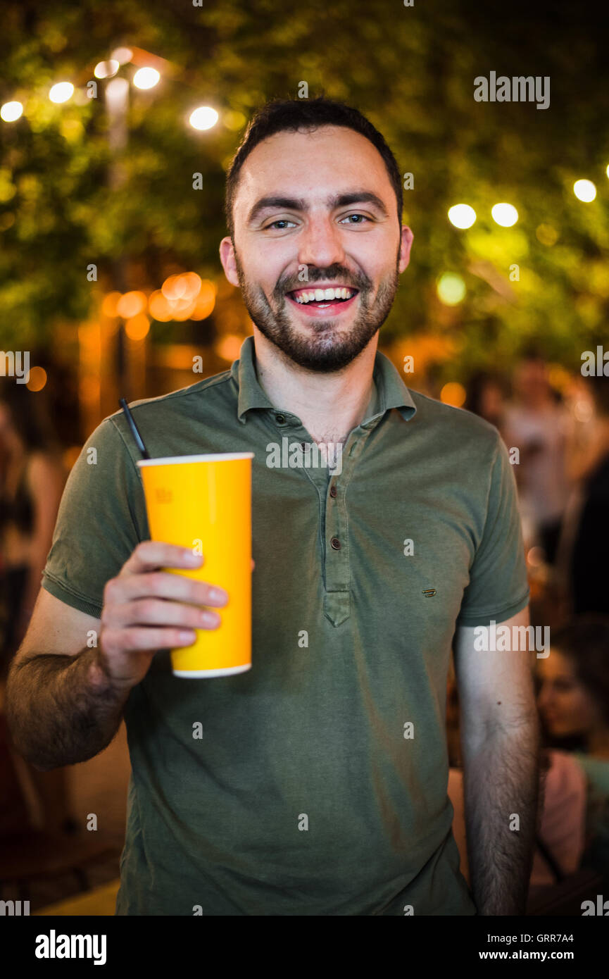 L'Homme barbu beau coctail potable ou de la bière en plein air au Café de la rue la nuit de la partie in park Banque D'Images