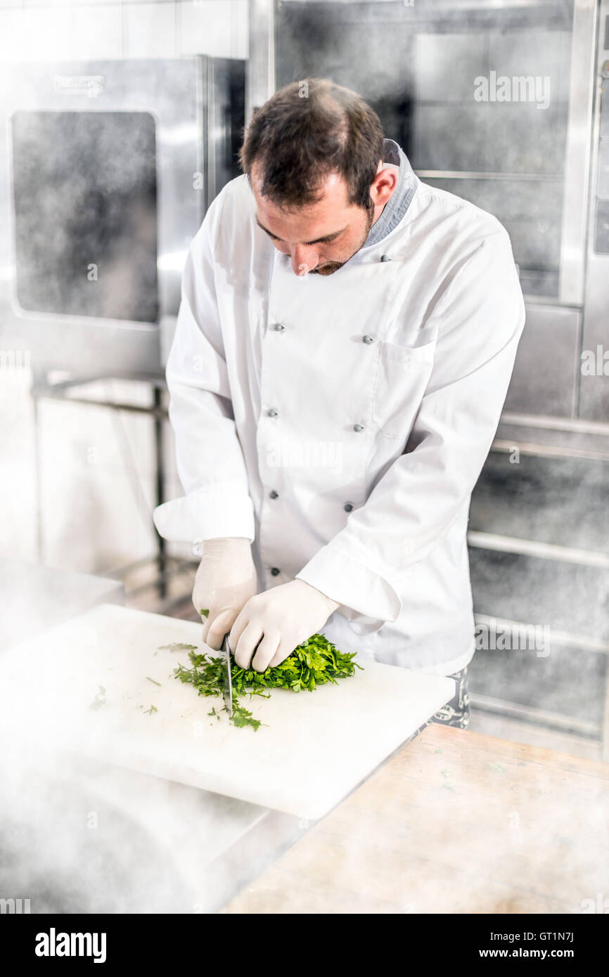 Male chef persil haché on cutting board Banque D'Images