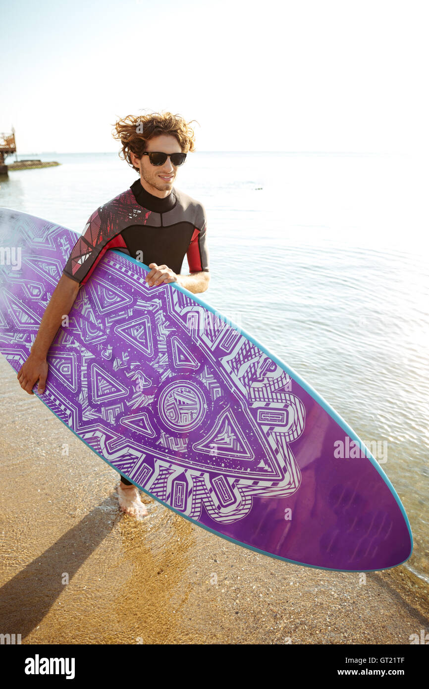 Happy young man with surfeur surf board s'exécutant sur la plage Banque D'Images