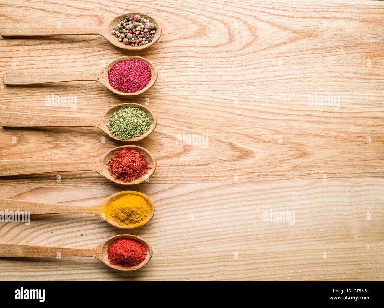 Assortiment d'épices colorées dans l'cuillères en bois sur la table en bois. Banque D'Images